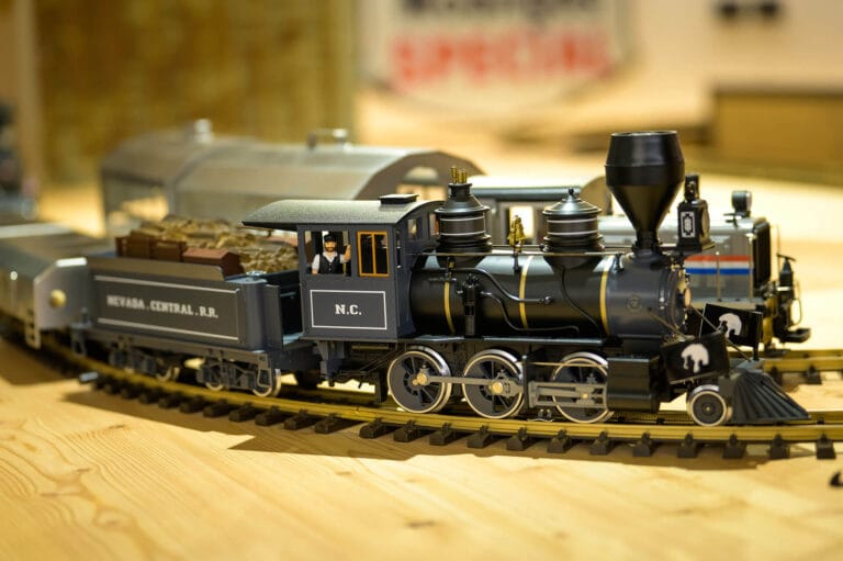 Modellino di locomotiva a vapore nera con vagone carbone della Nevada Central R.R., bandiera americana e personaggi a bordo