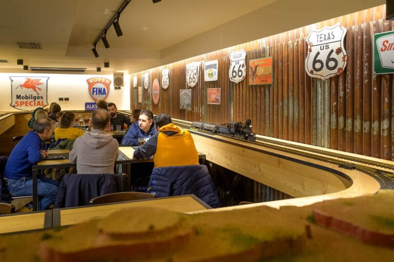Modellino di treno a vapore con vagoni che trasportano birra in movimento sui binari del ristorante, decorazioni a tema Route 66 e Far West sullo sfondo