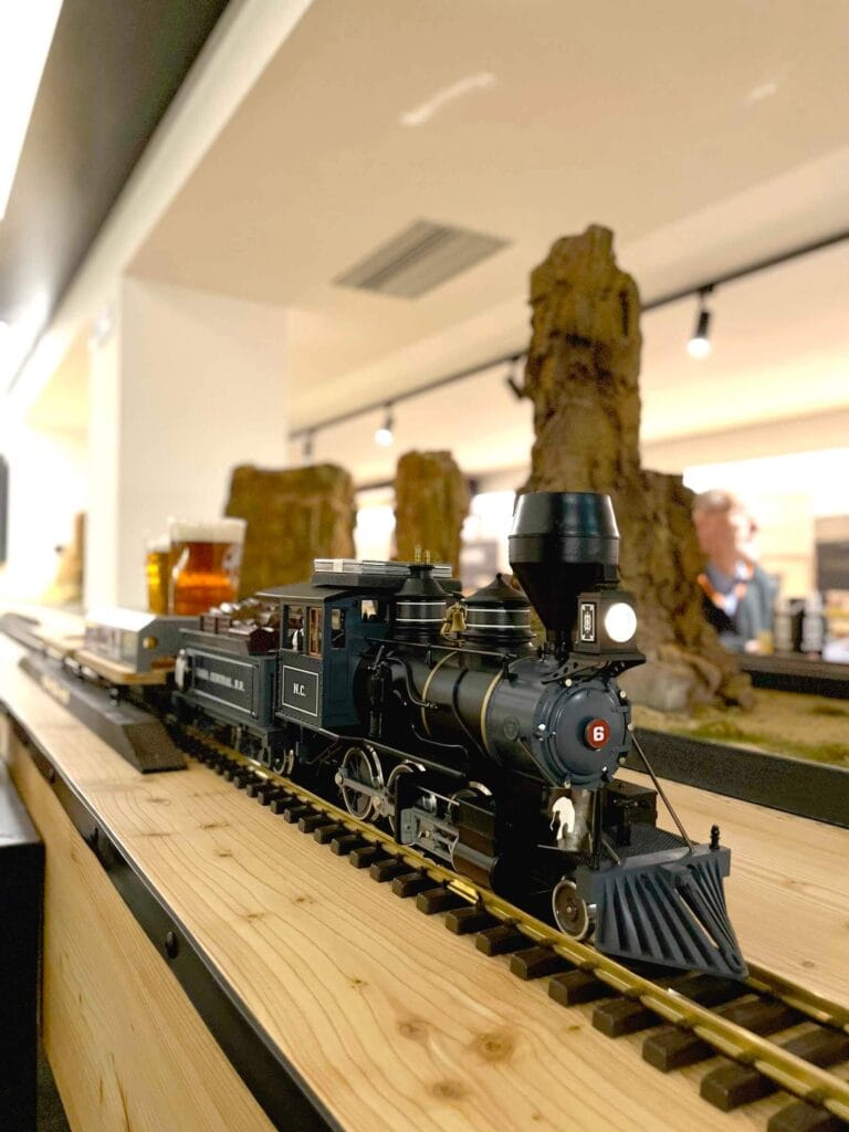 Black steam locomotive model with coal car from Nevada Central R.R., American flag and miniature figures onboard